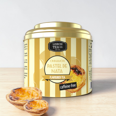 Lata dourada de chá cinnamon pastel de nata com dois pastéis de nata ao lado