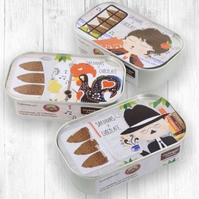 Três latas de chocolates em formato de sardinhas com ilustrações coloridas nas tampas