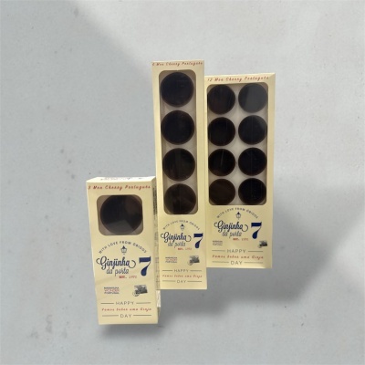 Caixas creme de Ginjinha da Porta com copos de licor escuros visíveis em diferentes quantidades.