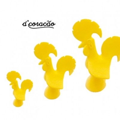 Três figuras amarelas de galos de plástico em diferentes tamanhos