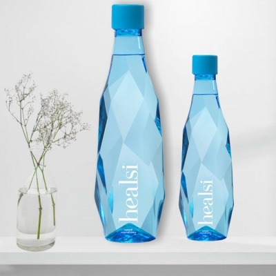 Duas garrafas azuis facetadas com texto 'healsi' e flores num frasco de vidro