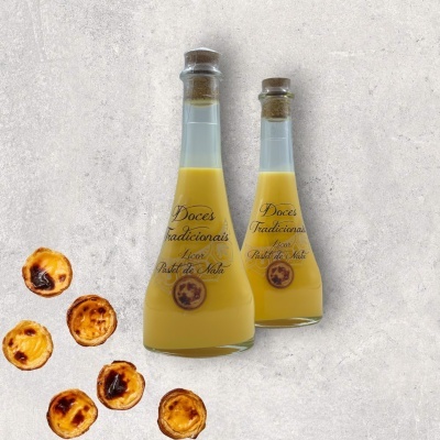 Duas garrafas de licor Pastel de Nata com pastéis de nata ao lado