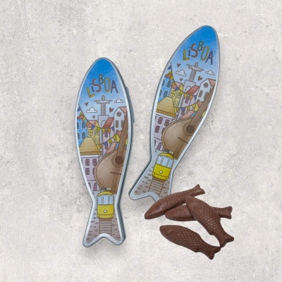 Dois blocos de notas em forma de peixe com ilustração da cidade de Lisboa e cinco peixes de chocolate castanho escuro.