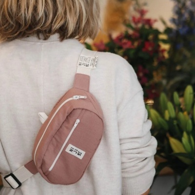 Mochila de pochete cor de rosa com fechos brancos usada por pessoa com camisola branca