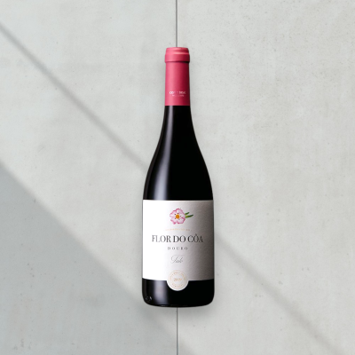 Garrafa de vinho FLOR DO CÔA com rótulo branco e tampa rosa num fundo cinzento