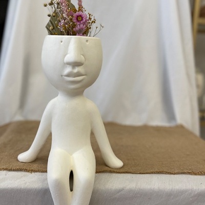 Vaso decorativo branco em forma de figura humana com flores secas