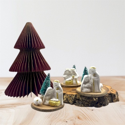 Presépios em cerâmica branca com detalhes dourados e árvore decorativa em papel castanho.