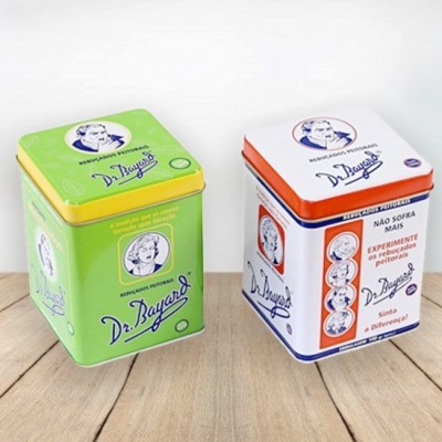 Dois recipientes metálicos Dr. Bayard, um verde e outro branco, com desenhos vintage e texto em português.