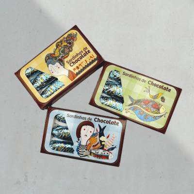 Caixas de sardinhas de chocolate com embalagens coloridas sobre superfície cinza