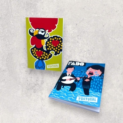 Dois blocos de notas coloridos com desenhos e texto 'PORTUGAL' sobre superfície cinza