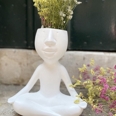 Vaso de cerâmica branco em forma de figura humana sentada com flores secas.