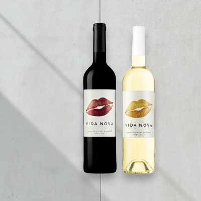 Duas garrafas de vinho VIDA NOVA, uma tinto e uma branco, com rótulos de lábios, sobre fundo cinza.
