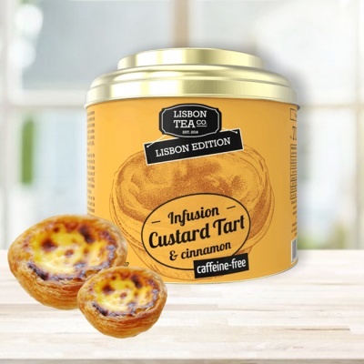 Lata de chá amarelo com tampa dourada e dois pastéis de nata