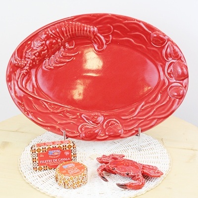 Prato vermelho com texturas de frutos do mar, conservas de peixe e figura decorativa de caranguejo