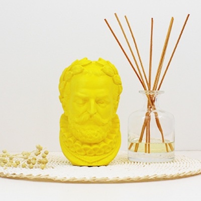 Busto decorativo amarelo ao lado de difusor de varetas em vidro