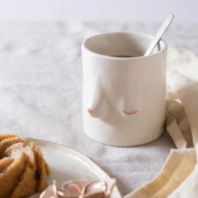 Caneca de cerâmica branca com design artístico em relevo de seios e colher
