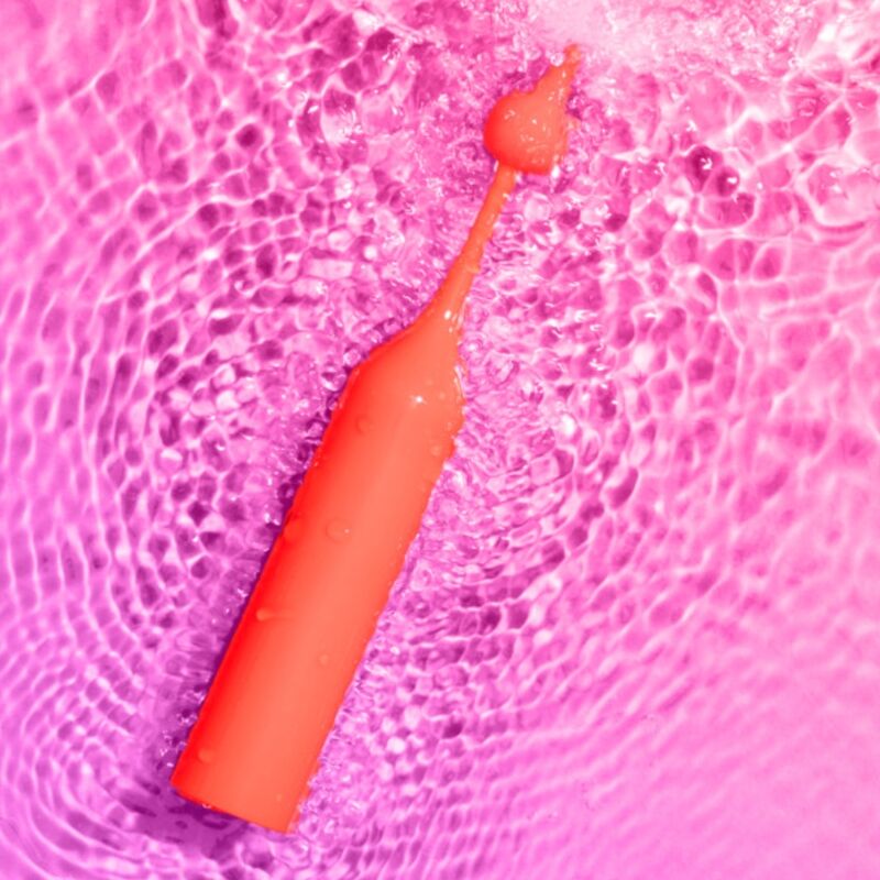 Vibrador pessoal laranja sobre superfície rosa ondulada