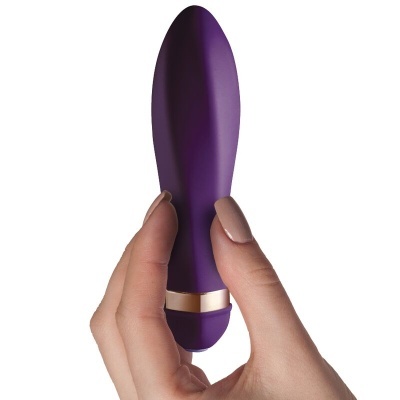 Vibrador pequeno roxo com detalhe dourado segurado por uma mão