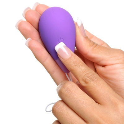 Dispositivo eletrônico roxo em forma oval segurado por mãos com unhas brancas