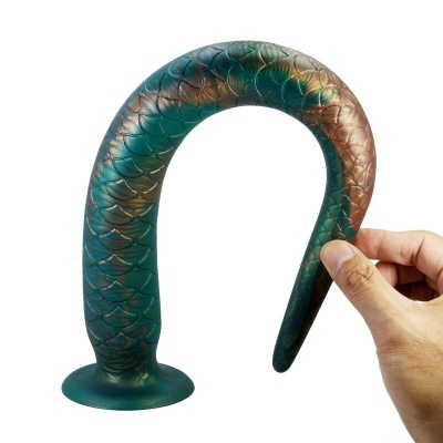 Objeto com textura de escamas em verde e castanho, curvado e segurado por uma mão