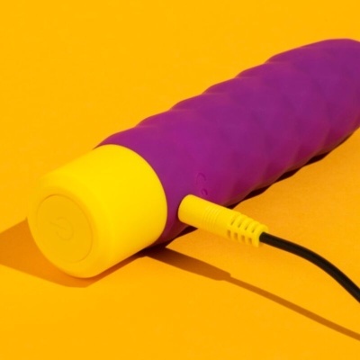 Vibrador roxo com base amarela e cabo de carregamento