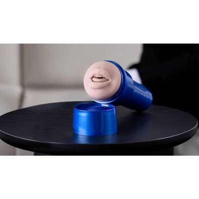 Dispositivo sexual masculino azul com ponta em silicone cor de pele em cima de mesa preta