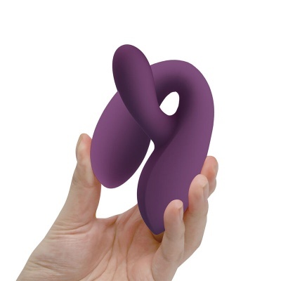 Produto curvo roxo em silicone numa mão com fundo branco