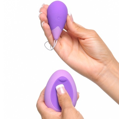 Aparelho pequeno roxo em silicone segurado por mãos femininas com unhas feitas