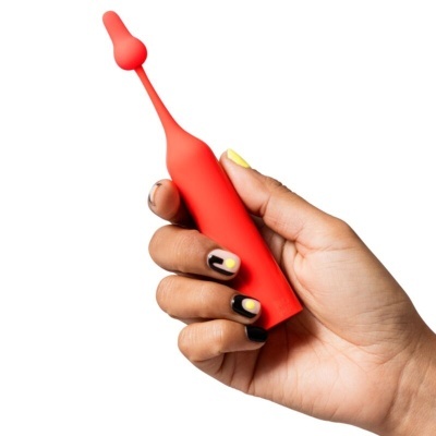 Mão segurando objeto vermelho de silicone com manicure artística preta e amarela