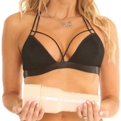 Mulher loira em biquíni preto segurando objeto cilíndrico rosa claro