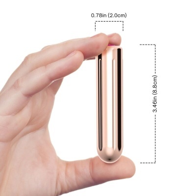 Dispositivo dourado metálico brilhante segurado pela mão com medidas indicadas.