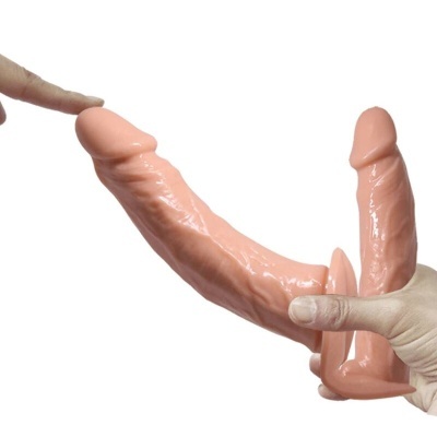 Dildo duplo flexível cor de pele com textura realista sendo segurado por uma mão