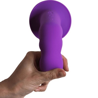 Objeto roxo de silicone com ventosa na base e textura ondulada, segurado por uma mão