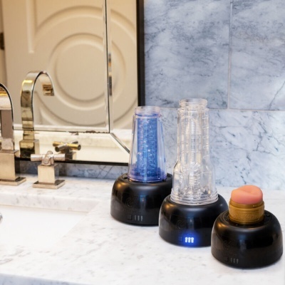 Dispositivos com bases pretas e objetos transparentes em bancada de mármore perto de espelho e torneira