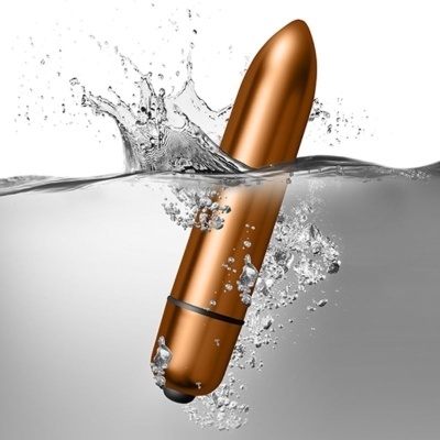 Vibrador dourado metálico em forma de batom submerso em água com bolhas