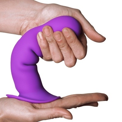 Produto de silicone roxo curvado com base plana, segurado por mãos