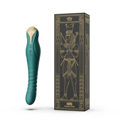 Vibrador verde com detalhes dourados ao lado de caixa preta com ilustrações douradas e texto KING VIBRATING VIBRATOR.