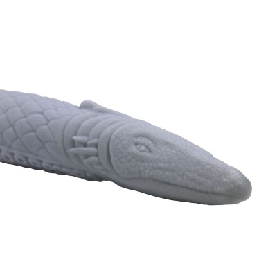 Objeto cinzento em forma de cabeça de réptil com textura de escamas