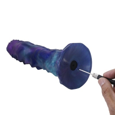 Objeto azul e roxo com textura irregular e base octogonal sendo perfurado por agulha