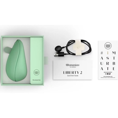 Produto verde com forma ergonómica, cabo USB, guia rápido Womanizer LIBERTY 2 e cartão com texto