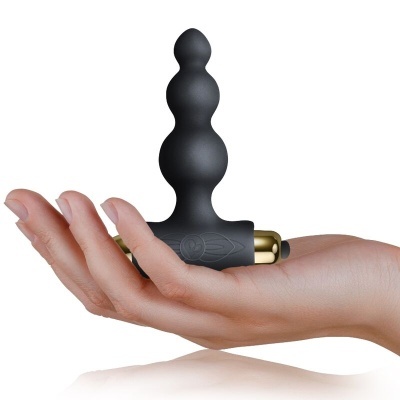 Plug anal preto em silicone com base dourada numa mão