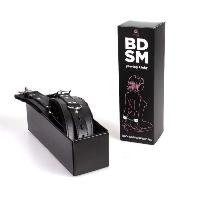 Algemas pretas com fivelas numa caixa preta ao lado da embalagem preta com texto BD SM playing kinky