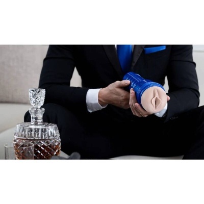 Homem de fato segurando brinquedo adulto azul junto a decantador de cristal