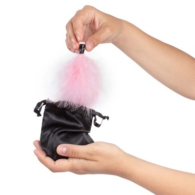 Mãos a segurar saco preto com objeto peludo rosa