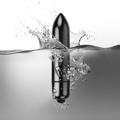 Vibrador preto metálico submerso parcial em água com bolhas e jato de água na superfície