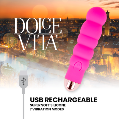 Vibrador rosa com textura ondulada e carregamento USB em fundo de cidade ao pôr do sol