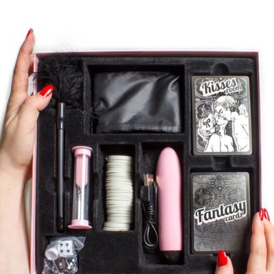Conjunto de jogo erótico com vários acessórios organizados numa caixa rosa com interior em veludo preto