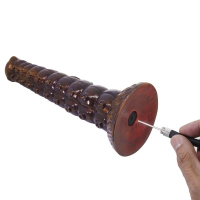 Objecto castanho cónico com textura sendo perfurado por ferramenta de metal