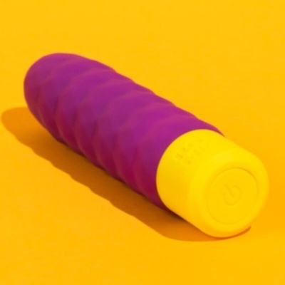 Dispositivo roxo e amarelo com botão de ligar em fundo amarelo