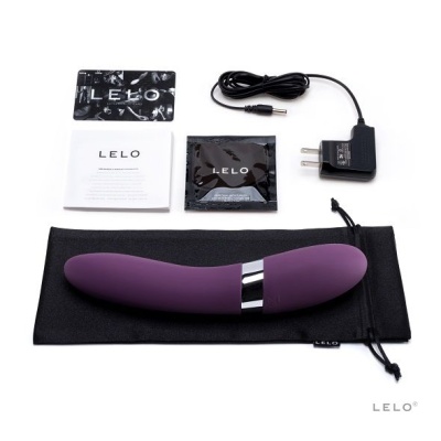 Kit com vibrador roxo em silicone, carregador, embalagens pretas e folheto branco com texto LELO, sobre saco preto de tecido